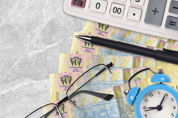 1 Ukrainian hryvnia bills and calculator with glasses and pen. Business loan or tax payment season concept. Time to pay taxes