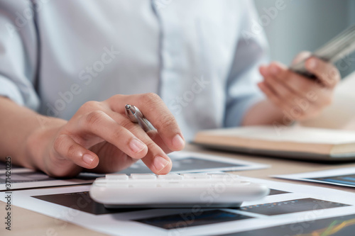 Fotomural businesswoman or an accountant uses a calculator to calculate prices