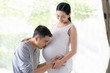 © Sukjai Photo - Asian husband is kiss his beautiful pregnant wife with love and they smiling together with happiness moment, concept of love, relation, expectation and  parenthood in  family lifestyle.