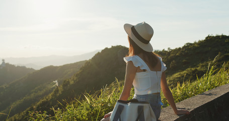 Canvas Print - Woman enjoy the sunset view and sit on the mountain