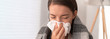© Maridav - Sick woman feeling unwell staying home. Young girl with flu symptoms coughing in tissue covering nose when sneezing as COVID 19 prevention. Panoramic crop.