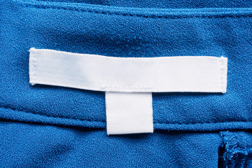 white blank laundry care clothes label on blue fabric background