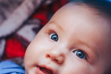 Wall Mural - A baby grimaces at the camera, a newborn baby with blue eyes and blond hair.