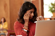 © SuperStock - Portrait of young ethnic woman wearing orange blouse sitting at bar in kitchen of downtown loft applying makeup