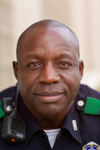 Close Up Portrait Of Uniformed Police Officer Sitting Outside Looking Towards Camera Smiling 