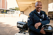 © SuperStock - Portrait of Police officer sitting on his motorcycle outside looking towards camera smiling
