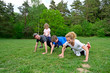 © Westend61 - Girl sitting on father back doing push-ups with family over grassy land in forest