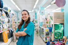 Smiling Female Groomer With Arms Crossed Standing In Pet Shop