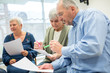 © Westend61 - Seniors in therapy group in retirement home writing down notes on sheets of paper
