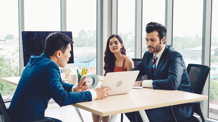 Wall Mural - Smart businessman and businesswoman talking discussion in group meeting at office table in a modern office interior. Business collaboration strategic planning and brainstorming of coworkers.