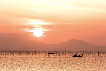 The beautiful seascape of ocean sunset background mountain and orange color clouds.