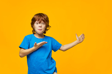 Wall Mural - An indignant red-haired boy shows with his hand to the side 