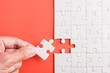 © sorapop - Top view flat lay of hand-holding last piece white paper jigsaw puzzle game last pieces put to place for solve problem complete mission, studio shot on a pink background, quiz calculation concept