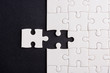 © sorapop - Top view flat lay of paper plain white jigsaw puzzle game texture last pieces for solve and place, studio shot on a black background, quiz calculation concept