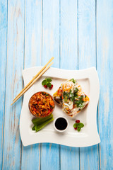 Chinese spring rolls, rice and sauces on wooden table
