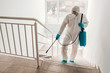 © Dusan Petkovic - Worker in sterile uniform, with gloves and facial mask sterilizing railing in school.