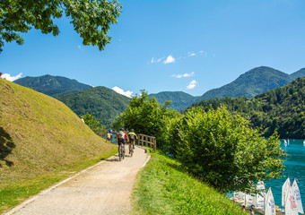 Two men riding their bicycles skirt Ledro Lake in Trentino Alto Adige, northern Italy, Europe.