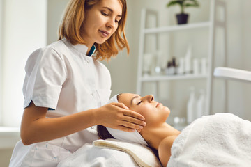 Facial skin care procedures. Beautician makes a massage procedure with a woman's face in a cosmetic clinic