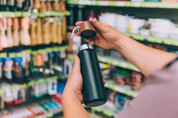 Wall Mural - A man in a supermarket holds a thermos in his hands.