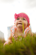 Cute Happy Blonde Blue-eyed Girl 6-7 Months Old Crawling On Grass And Looking Up. Conceptual Photo For Education, Healthy Childhood, Parenting. Perfect Caucasian Infant. Selective Focus