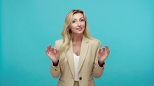 Talkative attractive middle aged woman in business suit speaking looking at camera, female life coach giving advice, training, advertising. Indoor studio shot isolated on blue background