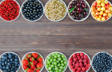 A set of berries in the round plates. Brown wooden background. Copy space.