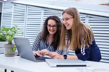 Two serious businesswomen girls discussing a business project, working together in the office, serious female consultant and client talking at a meeting, focused executive colleagues share ideas