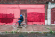 Inner city urban street with a teen riding his bike on the sidewalk, motion blur on bicycle