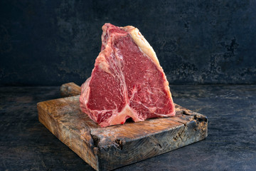 Wall Mural - Raw dry aged wagyu porterhouse beef steak offered as close-up on rustic wooden board with copy space