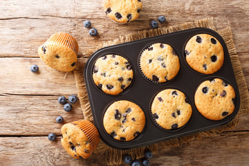 Wall Mural - Rustic blueberry muffins close-up in a baking dish on the table. horizontal top view from above