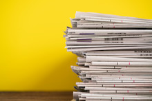Close Up Newspapers Folded And Stacked On Yellow Background On The Table