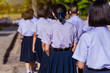 © pop_thailand - The back view of Asian high school students in white uniform are walking towards preparing to respect the national flag in the morning amidst the beautiful nature surrounding the