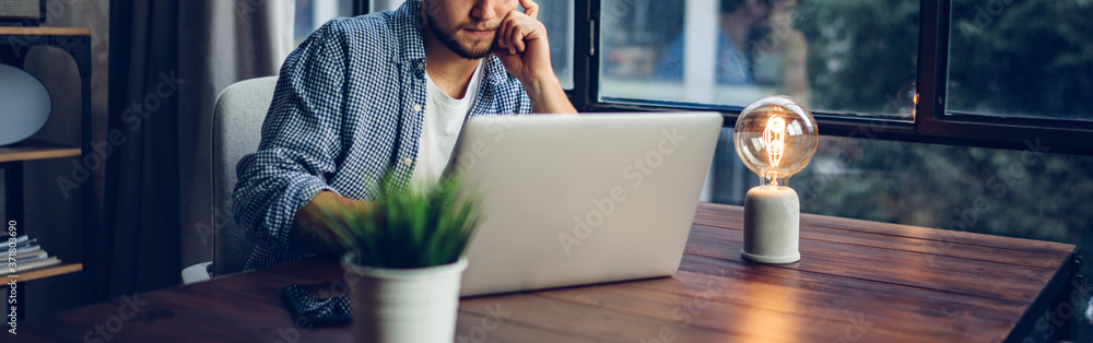 Young man working with a laptop. Freelancer connecting to internet via computer. Businessman at work - obrazy, fototapety, plakaty 