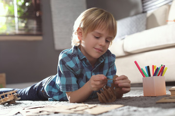 Poster - Little boy making cardboard toys on floor at home. Creative hobby