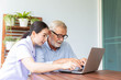 © PinkBlue - Nurse help senior retirement man working with laptop at home and feeling happy