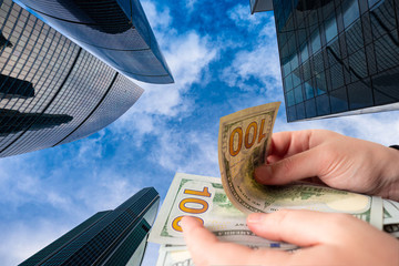 Hands with money on  background of skyscrapers. Skyscrapers as symbol of elite real estate. Glass high-rise buildings bottom view. Dollars. Realtor. Purchase real estate. Sale commercial real estate