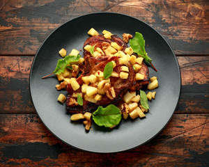 Wall Mural - Roasted Pork chops with caramelized apples, walnuts and sage in black plate on wooden table