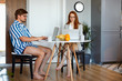© alfa27 - confident office workers at home during quarantine, young caucasian couple sit in pajamas at table using laptop