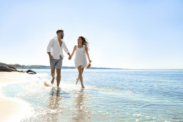 Happy young couple running on beach near sea. Honeymoon trip