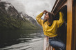 © Yehor Hanhalo - Brunette caucasian woman sits on the window of the wooden boat & feels freedom on background of Konigssee lake, rock mountain & clouds in rainy spring in Bavaria. Germany