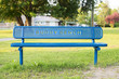 Blue buddy bench in park near school