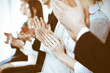 © rogerphoto - Business people clapping and applause at meeting or conference, close-up of hands. Group of unknown businessmen and women in modern white office. Success teamwork or corporate coaching concept