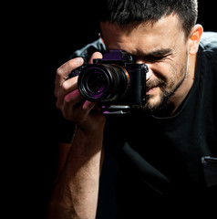 Wall Mural - The person is holding a camera and is set up for shooting. The photographer looks into the camera's viewfinder and takes pictures. Object on a black background.