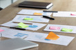 Close up paper marketing research reports or economic sales statistics documents with colorful handwritten notes on stickers lying on wooden table, workflow planning organization process concept.