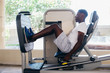 © twinsterphoto - Back view of African American man doing exercise on leg press during fitness training in modern gym.