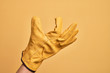 © Krakenimages.com - Hand of caucasian young man with gardener glove over isolated yellow background picking and taking invisible thing, holding object with fingers showing space