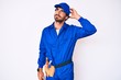 © Krakenimages.com - Handsome young man with curly hair and bear weaing handyman uniform confuse and wondering about question. uncertain with doubt, thinking with hand on head. pensive concept.