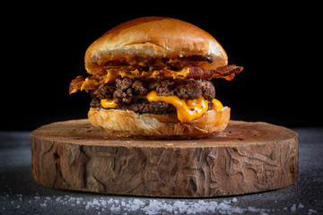 Two smash burgers with cheddar cheese, bacon and garlic sauce. Rustic craft burger.