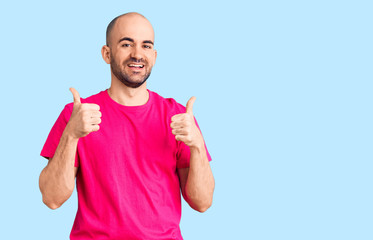 Young handsome man wearing casual t shirt success sign doing positive gesture with hand, thumbs up smiling and happy. cheerful expression and winner gesture.