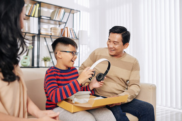 Poster - Excited happy preteen Vietnamese boy taking headphones out of giftbox that parents gave him